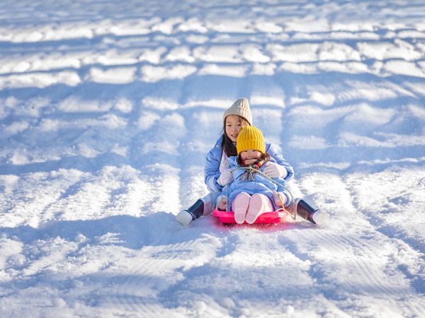 Two children tobogganing at Corin Forest