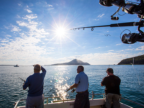 three men fishing on a boat in port stephens