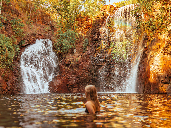 Surrounded by lush forest, a woman cools off in Florence Falls, just one of many incredible things to do in the Northern Territory.