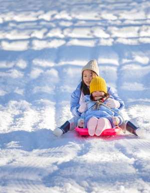 Two children tobogganing at Corin Forest