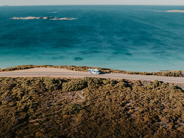 Aerial view of the Polaris 6 cruising along a coastal road with sweeping beach views.