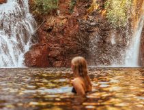 Surrounded by lush forest, a woman cools off in Florence Falls, just one of many incredible things to do in the Northern Territory.