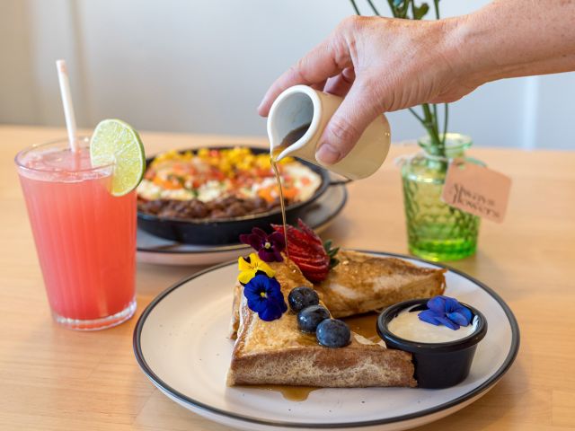 pouring sweet syrup over a breakfast plate at Frida’s Cantina, Kiama restaurants