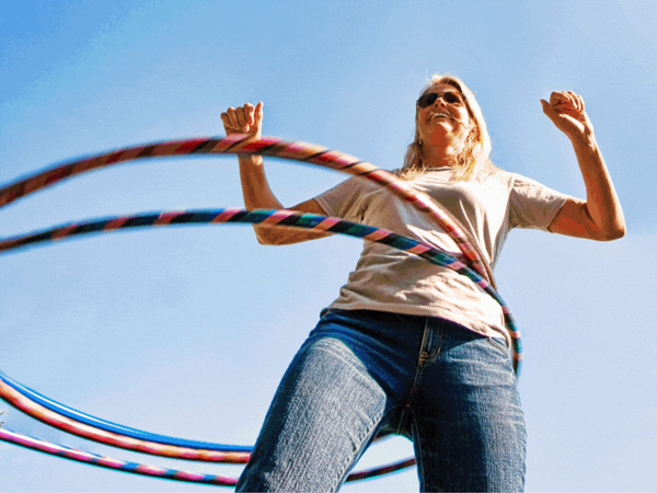 Woman hula hooping on sunny day