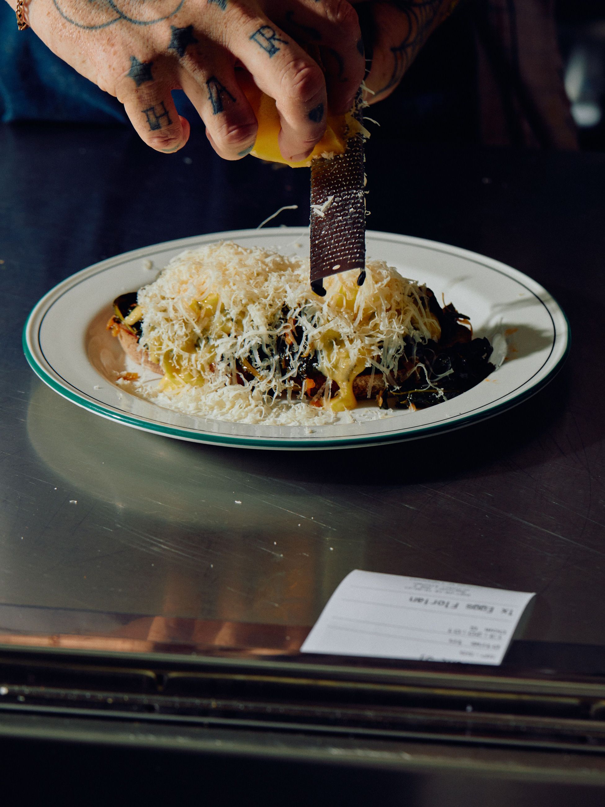 grating cheese over a plated dish at Florian Eatery