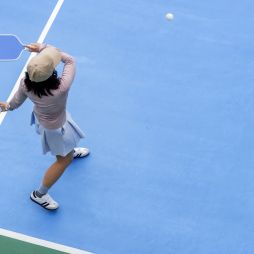 top view of woman playing pickleball, holding paddle to return ball in pickleball court