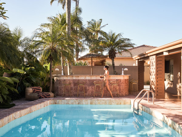 a woman walking by the pool at Swell Hotel Byron Bay