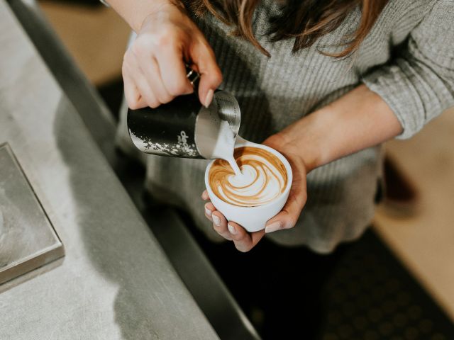 person pouring cup of coffee in white ceramic cup
