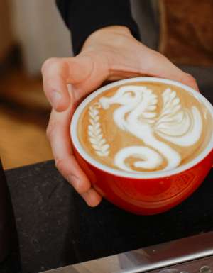 barista pouring froth milk on coffee cup prepared coffee latte art at bar counter