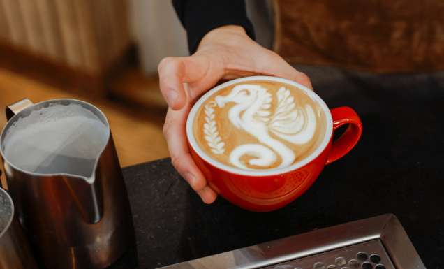 barista pouring froth milk on coffee cup prepared coffee latte art at bar counter