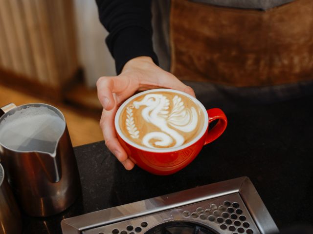 barista pouring froth milk on coffee cup prepared coffee latte art at bar counter