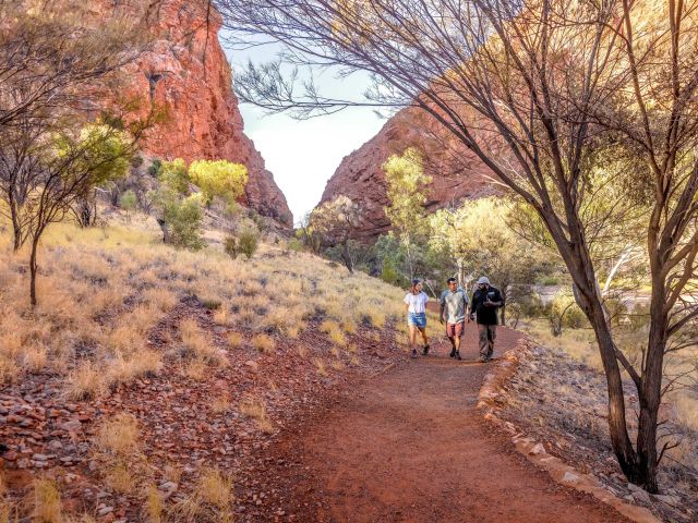 three people walking on path through simpsons gap near alice springs