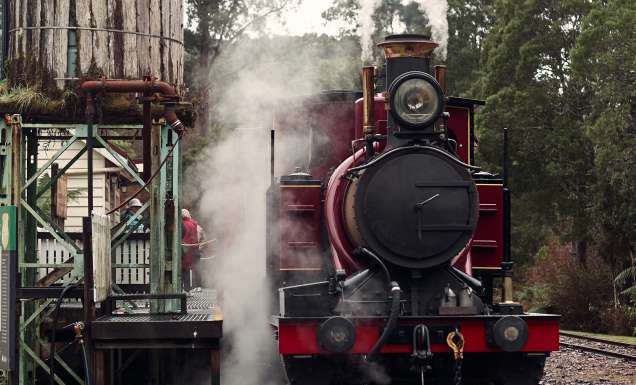 A red historic train pulled up at a station.