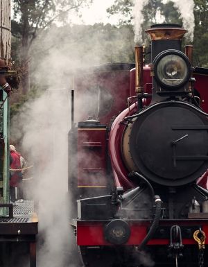 A red historic train pulled up at a station.