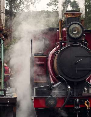 A red historic train pulled up at a station.