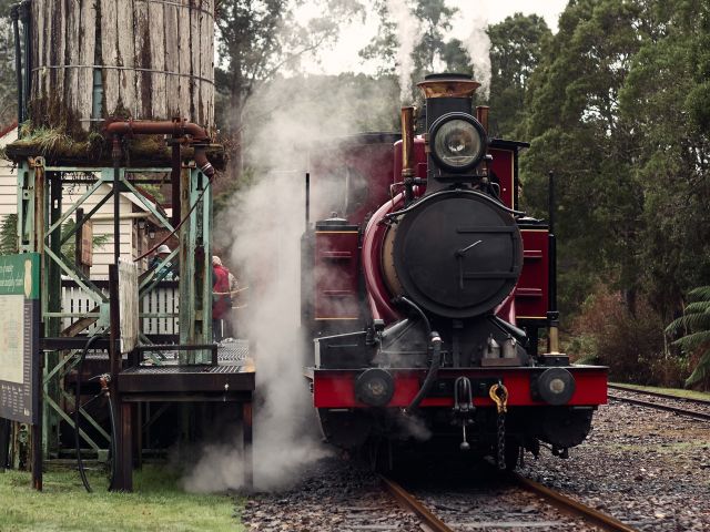 A red historic train pulled up at a station.