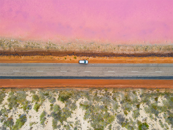 A car parked on the side of the road next to a pink lake