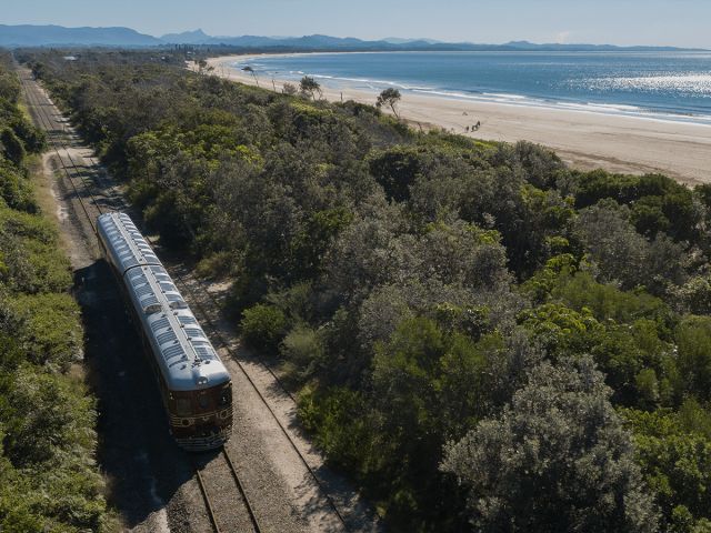 A historic train passing tracks near the beach