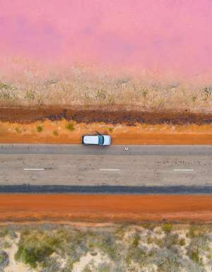 A car parked on the side of the road next to a pink lake