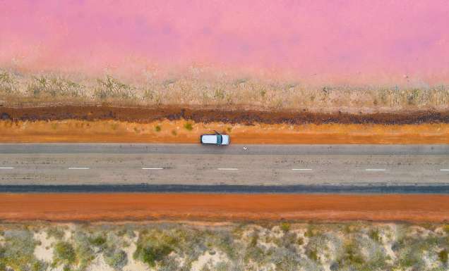 A car parked on the side of the road next to a pink lake