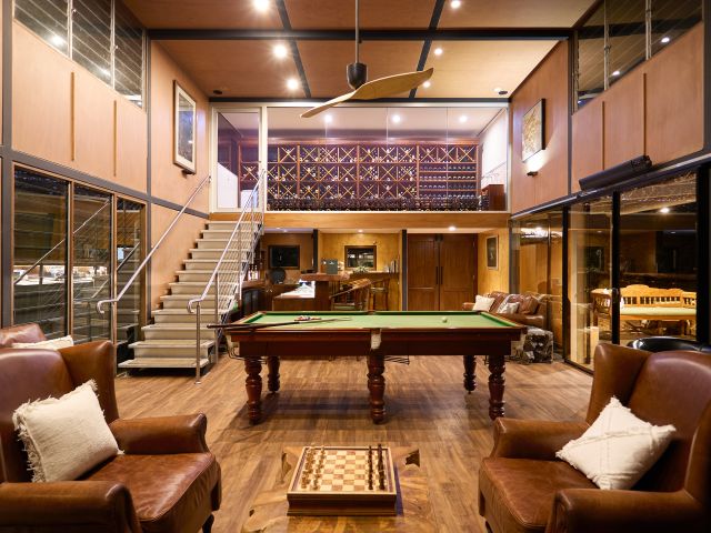 A two-level timber-clad wine cellar and bar with a pool table in the middle