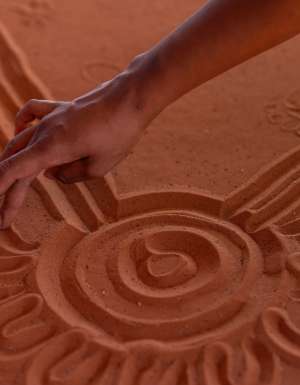A hand maps the Mala Walk in the red sand of Uluru