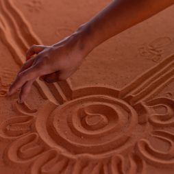 A hand maps the Mala Walk in the red sand of Uluru