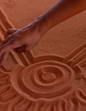 A hand maps the Mala Walk in the red sand of Uluru