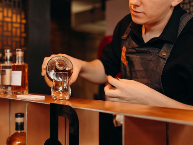 a bartender holding a glass of rum at New Norfolk Distillery