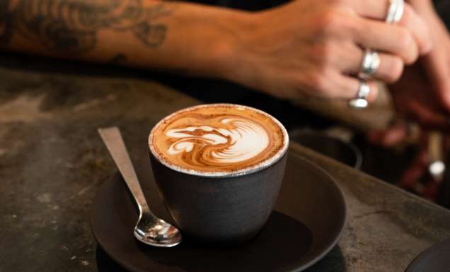 single o surry hills barista leans on bench near coffee