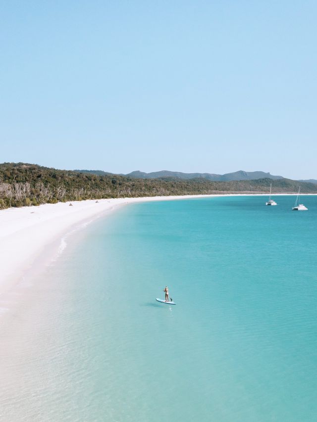 Woman stand-up paddleboarding in the water at Whitehaven Beach