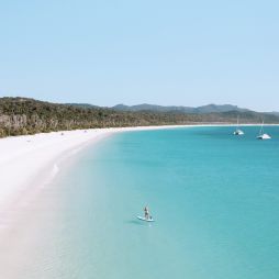 Woman stand-up paddleboarding in the water at Whitehaven Beach