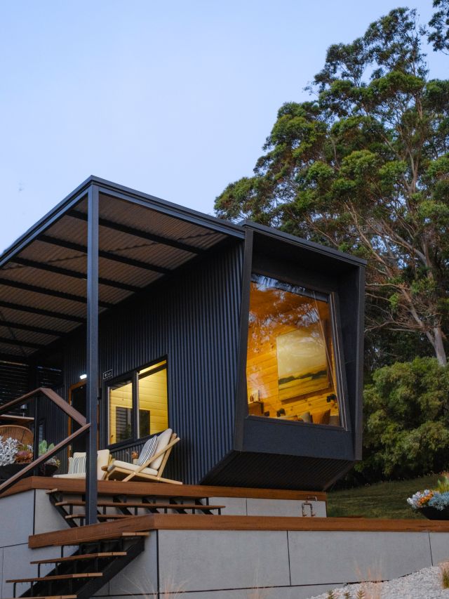 A black cabin at night with a light on