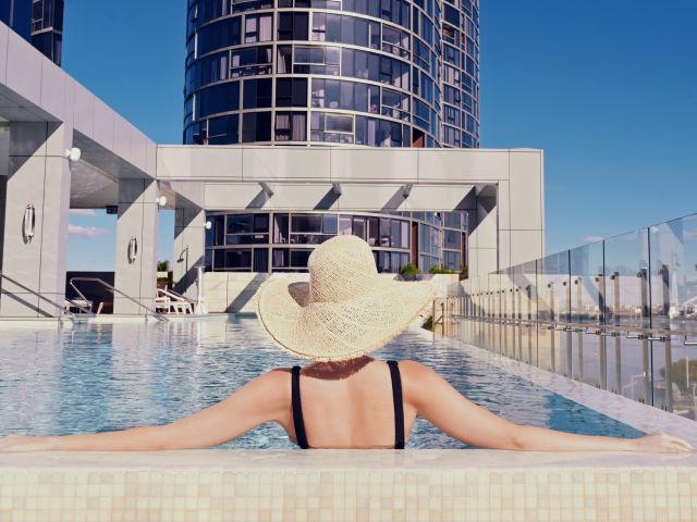 a woman wearing a hat relaxing by the pool at The Ritz-Carlton, Perth