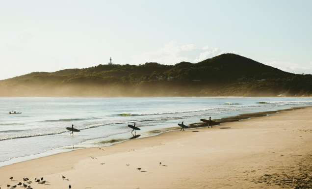 Surfers catching morning waves at Belongil Beach, Byron Bay