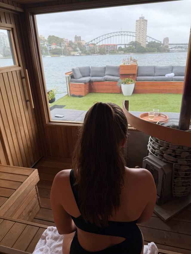 Woman sitting in Wellness Afloat The Ark floating sauna in Sydney Harbour