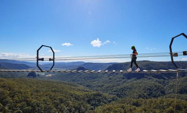 woman walking over Happitat wobbly bridge