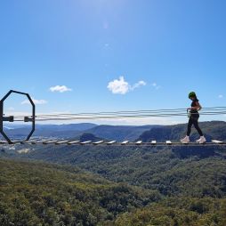 woman walking over Happitat wobbly bridge