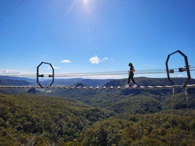 woman walking over Happitat wobbly bridge