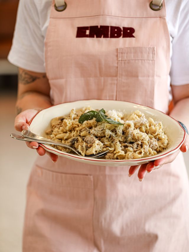 a server at Embr holding a plate of pasta
