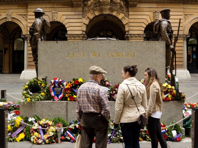 Three people standing in front of an Anzac Day memorial
