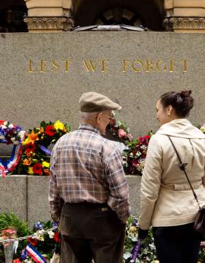 Three people standing in front of an Anzac Day memorial