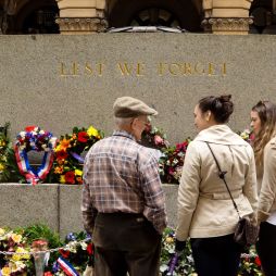 Three people standing in front of an Anzac Day memorial