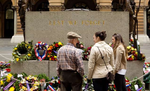 Three people standing in front of an Anzac Day memorial
