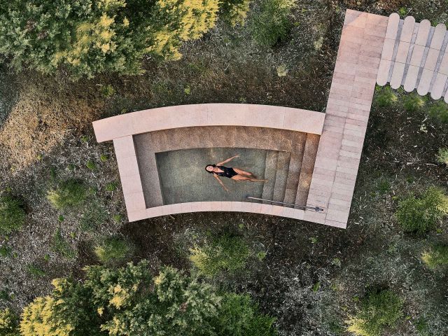 From an aerial view, a woman drifts peacefully across still, crystal-clear water.