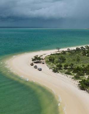 Aerial shot of East Arnhem’s coastline as cars trace the curve of the shore.
