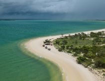 Aerial shot of East Arnhem’s coastline as cars trace the curve of the shore.