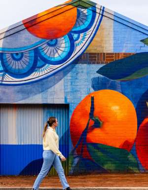 A woman walking past a food mural, something you can spot during A Taste of Italy Griffith.