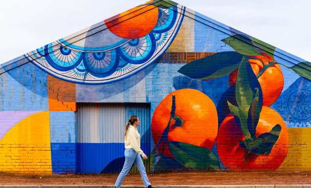 A woman walking past a food mural, something you can spot during A Taste of Italy Griffith.