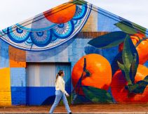 A woman walking past a food mural, something you can spot during A Taste of Italy Griffith.